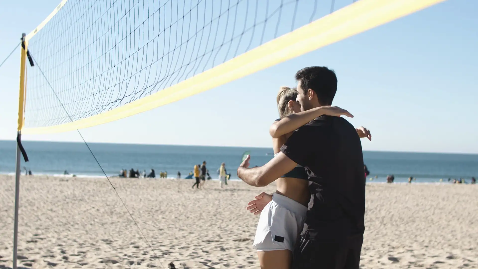 A couple celebrates on the beach with a high five and a hug